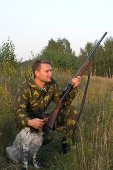 Man in camouflage with a gun and russian hunting spaniel.