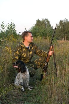 Man in camouflage with a gun and russian hunting spaniel.