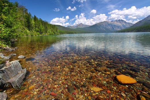 Brightly colored rocks seen through the crystal clear waters of Kintla Lake in Glacier National Park - USA.