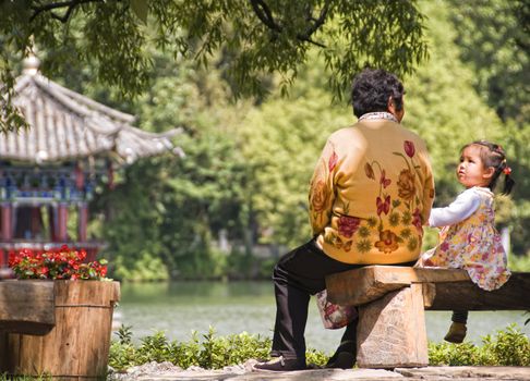 Young Chinese girl with her Grandmother in Jade Spring Park, Lijiang, China, July 9 2010. Approximately 280,000 people live in the Ancient City, of whom 66.7% are Naxi people.