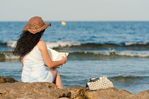 Woman ejoying a book with her feet in the water