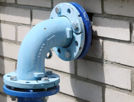 Blue painted pipe on the white bricks wall