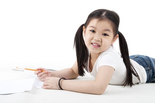 Little Asian girl drawing, lying on floor