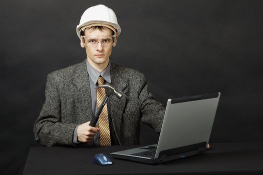 The man in a helmet with a hammer was going to repair the computer