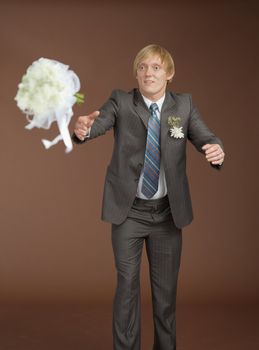 The groom catches a flying bouquet on a brown background