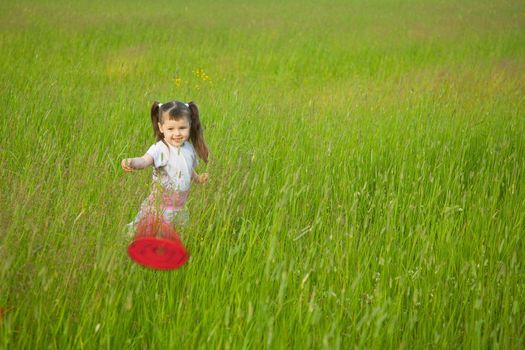 The little girl starts a flying disk in the field
