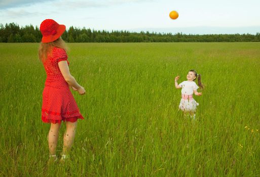 Mum and daughter play with a ball in the field