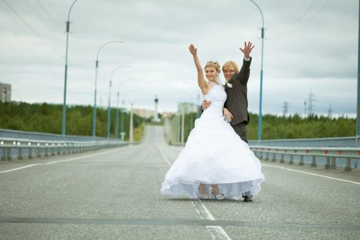 Newly married have fun standing on country highway