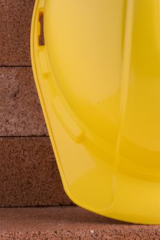 Yellow hard hat on a background of red bricks.