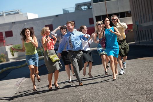 Group of hard working business men and women run down city street.