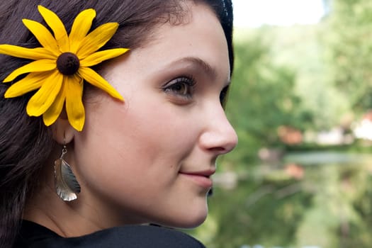 An attractive young woman wearing a black eyed susan wildflower in her hair.