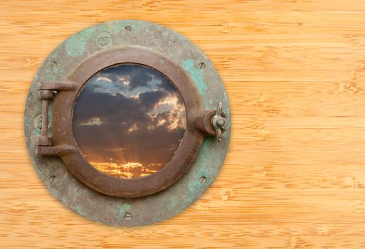 Antique Porthole with View of Sunset on a Bamboo Wall Background.