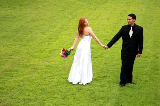 Bride and groom spinning on a green lawn