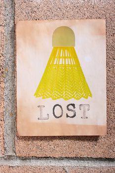 A lost sign with a yellow badminton shuttlecock hanging on a wall.