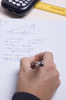 Student writing a math exam in a notebook.