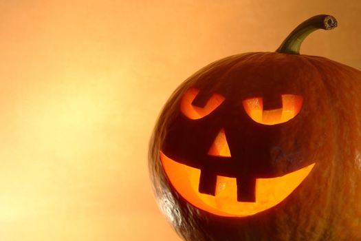 Closeup of glowing pumpkin head on yellow background with copy space