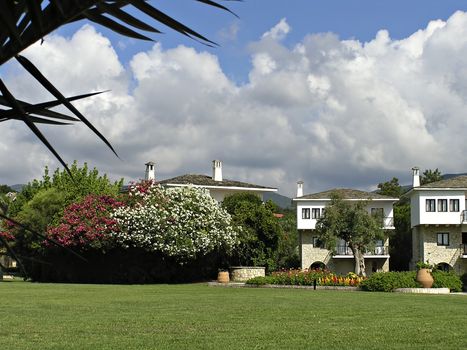 Guest houses with apartments, green grass and colorful flowers.