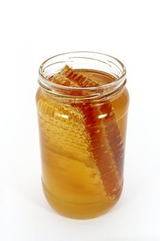 Glass jar full of honey with honeycomb, isolated on white