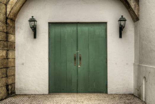 Green door closed in white wall, background of city.