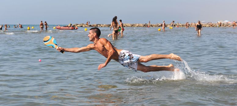 young man playing beach tennis in the sea