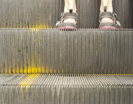 Two feet of a female traveller on an old escalator