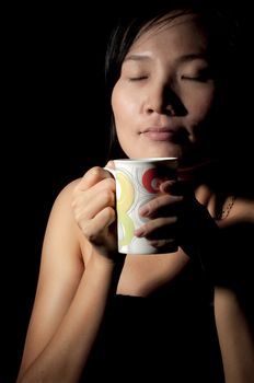 Attractive woman  with an aromatic coffee in hands isolated on black background