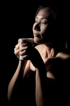 Attractive woman  with an aromatic coffee in hands isolated on black background