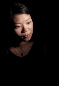 Soft contemplative look of beautiful asian woman on black background