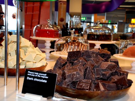 White chocolate and dark chocolate, cut into big parts, with in the background big beautiful cakes. A chocolate shop in the amsterdam's airport.