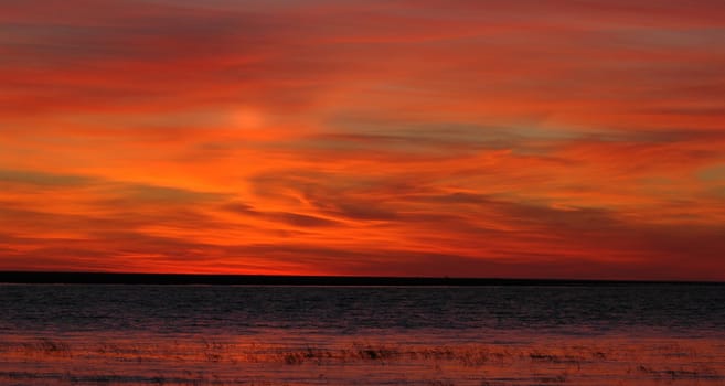 Blood-red decline on Ladoga lake. The come sun has painted blood-red color the sky and clouds over lake Ladoga 