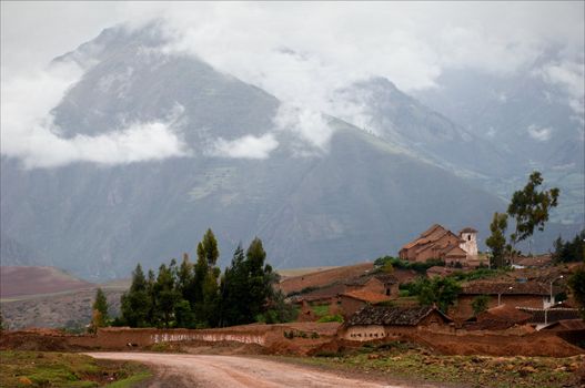 Small village in the Andes. Small structures against the mountains which tops are covered by clouds. 