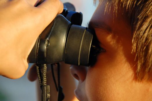 teen boy looking through black binoculars closeup