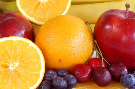 close up of fruits orange, cherry, apple, banana, blue berries