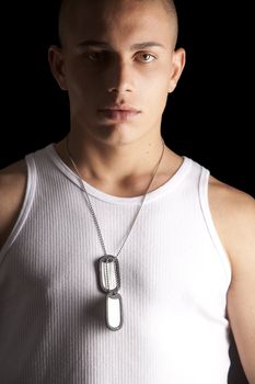 A good looking, muscular built, man on a black background with dog tags.