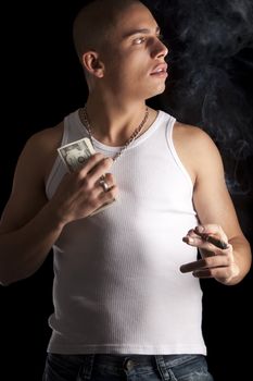 A good looking, muscular built, man on a black background smoking cigar.