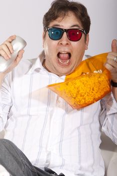 A young man watching a movie in 3D, with stylish 3D glasses and eating popcorn.