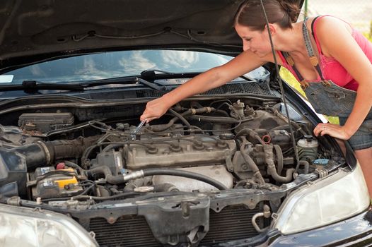 Young woman repairing her car
