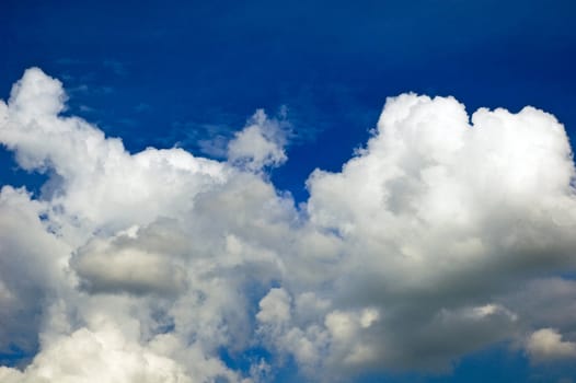 A horizontal shot of bright blue sky with puffy white clouds.