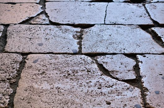 Rough texture of wet cobblestones. Ancient road