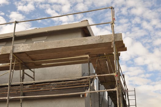 New Home Construction Scaffolding with Blue Sky and Clouds in Background