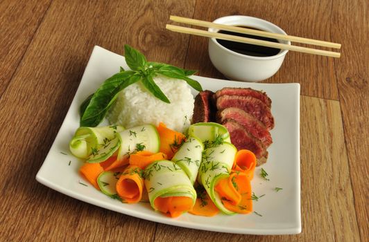 Slices of veal meat with the blood with rice, zucchini and carrots with soy sauce