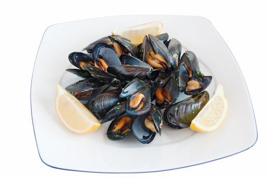 cooked mussels on a plate with lemon isolated with clipping path