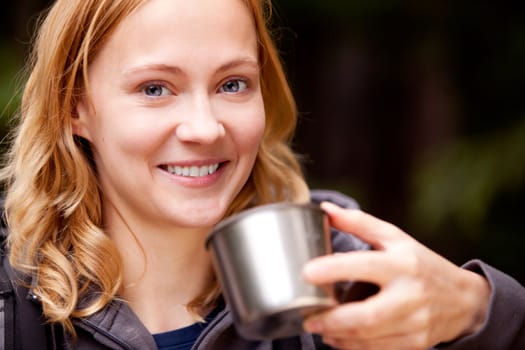 A young beautiful woman outdoors on a campnig trip taking a drink