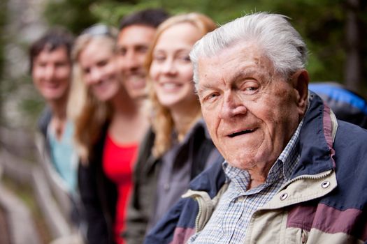 A portrait of a grandfather type man with a group of young people