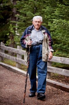 An elderly man walking on a path through the forest