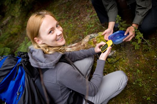 A young woman finding a geocache in the forest