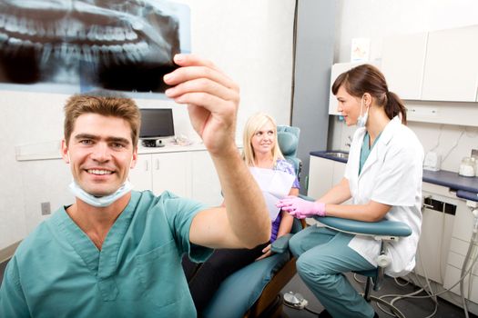 A dentist holding an x-ray while looking and smiling at the camera