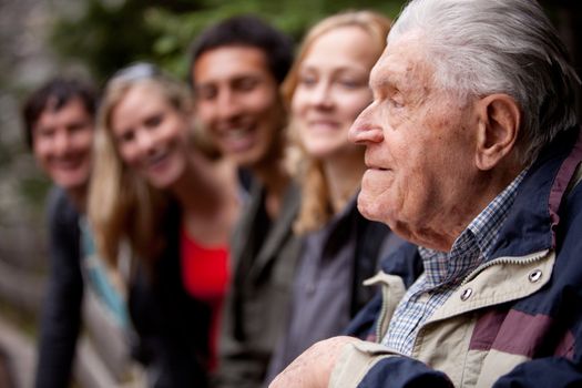 An elderly man telling stories to a group of young people in the forest