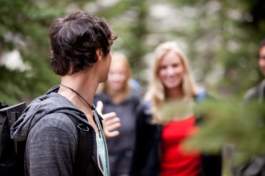 A group of people on a hike, a man waiting for a girl