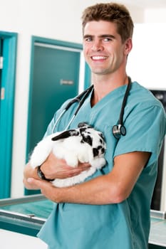 A male vet holding a rabbit in a small animal vet clinic
